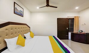 A hotel room with a bed, a ceiling fan, a door, and a window with curtains.