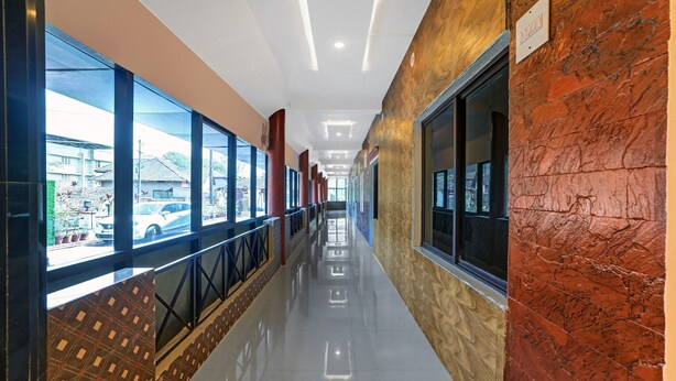 A corridor with large windows, a reflective floor, and a brick wall. - Itsy Hotels Regalia Grand, 500 Mtrs From Madikeri Fort (Madikeri)