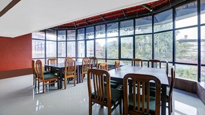 A dining area with tables and chairs, large windows, and a red ceiling. - Itsy Hotels Regalia Grand, 500 Mtrs From Madikeri Fort (Madikeri)