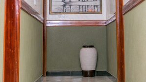 A hallway with a marble floor, a painting of trees, and a vase. - Beautiful woman hotel (Kampala)