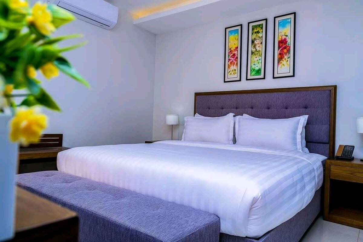 A neatly arranged bedroom with a large bed, a bedside table, a nightstand, and a bench.