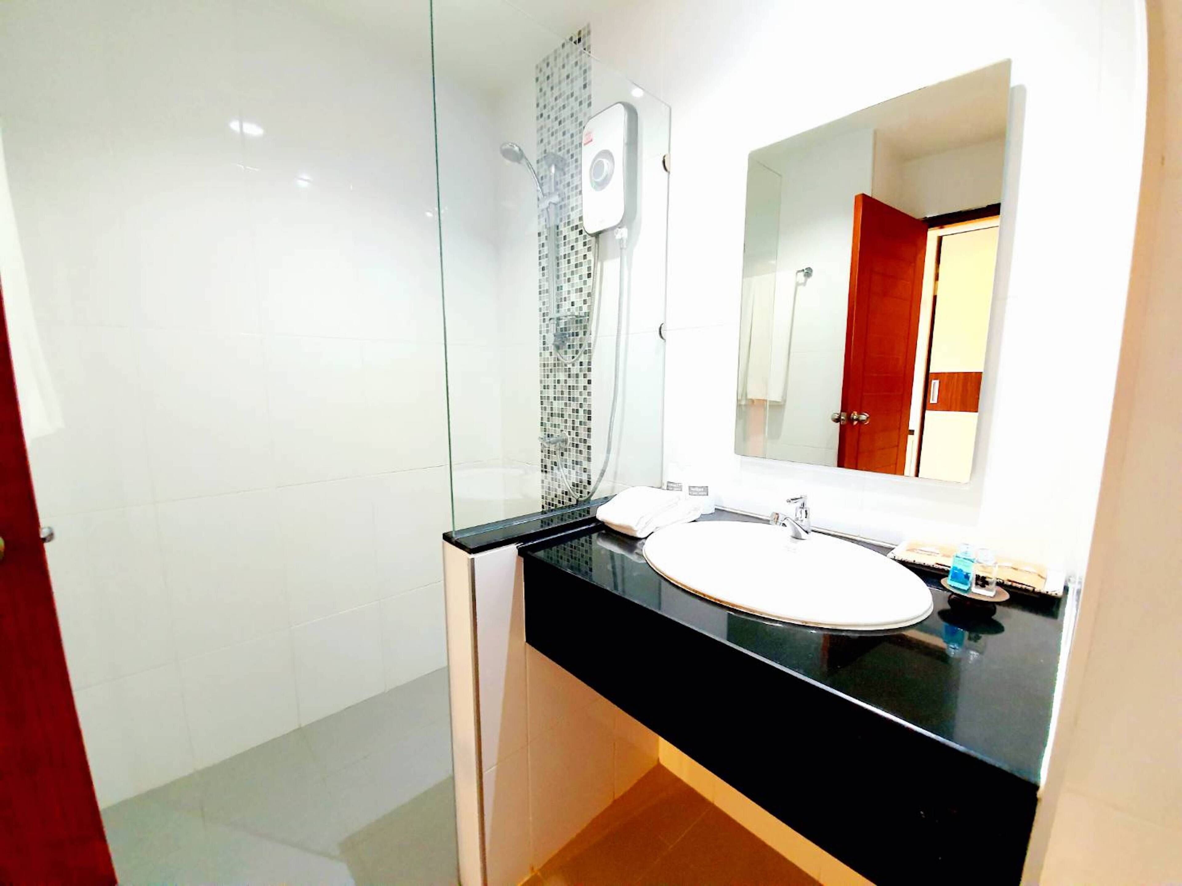 A modern bathroom with a glass shower enclosure, a white sink, and a large mirror.