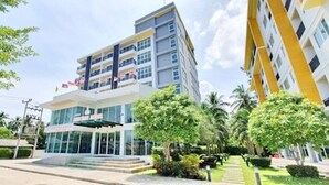 Un hôtel à plusieurs étages, doté d’un design moderne, avec une entrée en verre et un espace jardin aménagé.