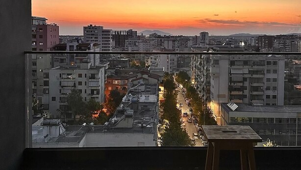 A balcony with a view of a cityscape at sunset.