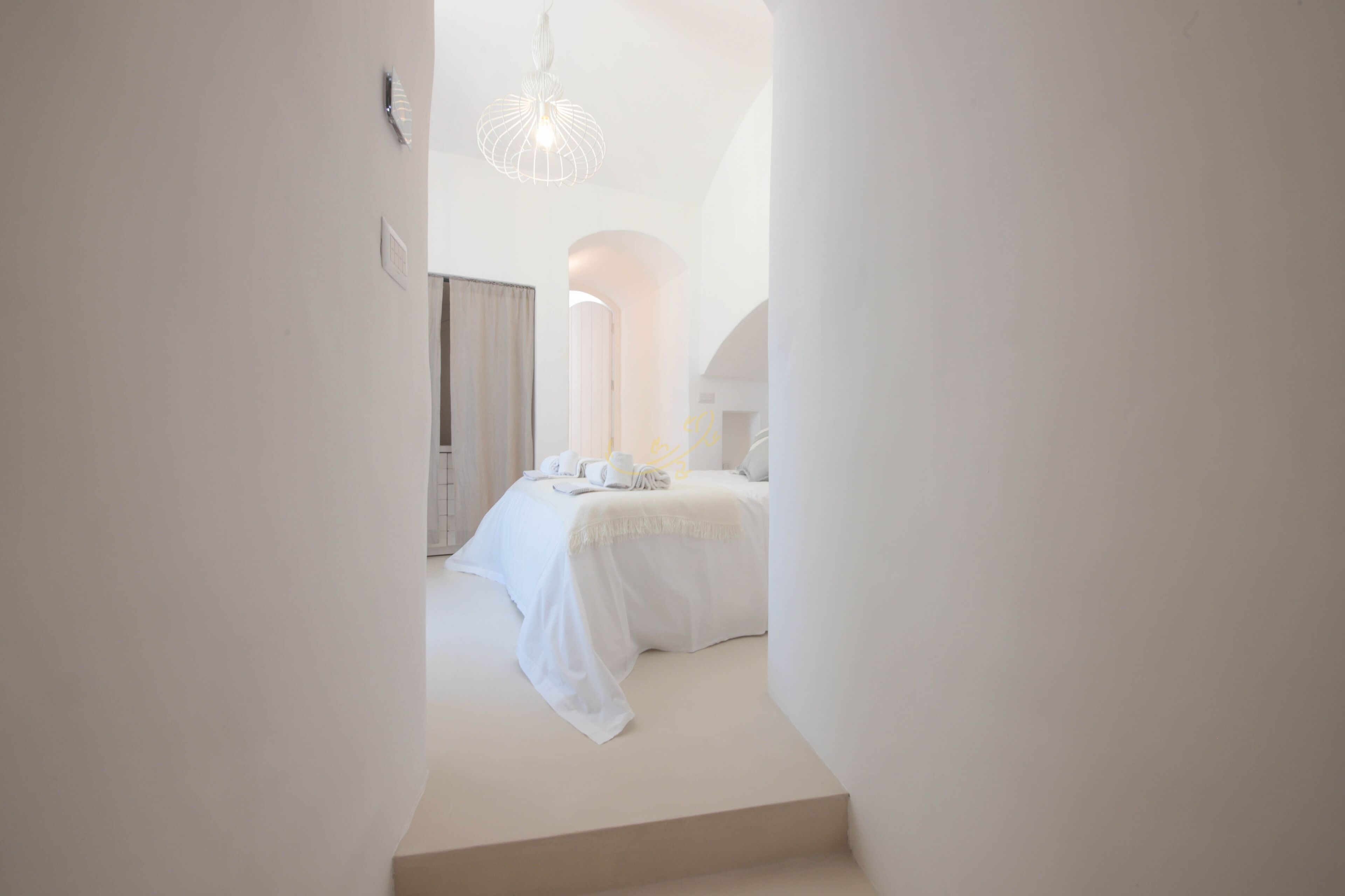Ein modernes, minimalistisches Schlafzimmer mit Bett, Nachttisch und einer Pendelleuchte.