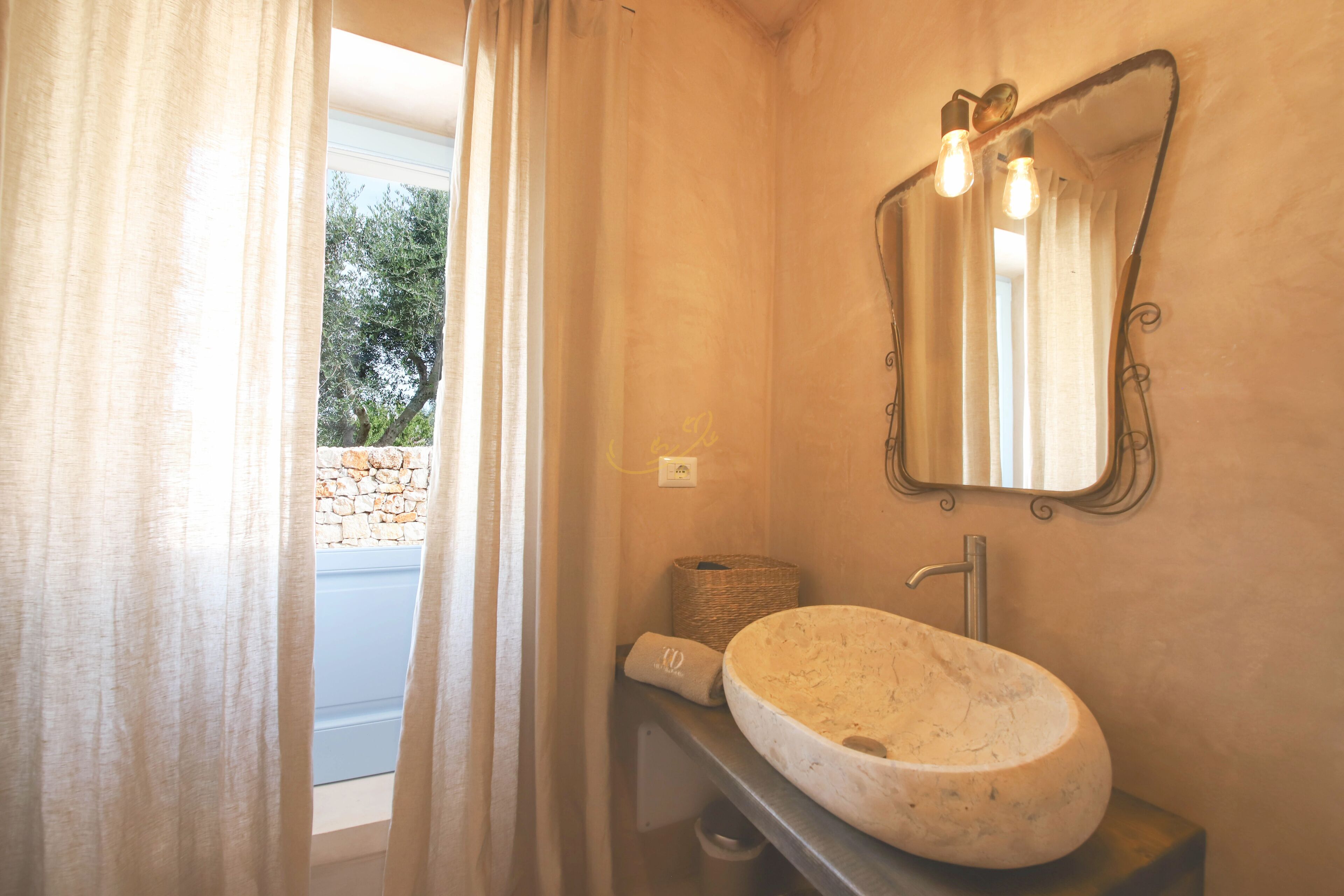 Une salle de bain avec un lavabo en pierre, un miroir et un panier.