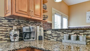 A kitchen with wooden cabinets, a coffee maker, and a tiled backsplash.