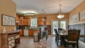 A kitchen with wooden cabinets, a granite countertop, and a dining area with a table and chairs.