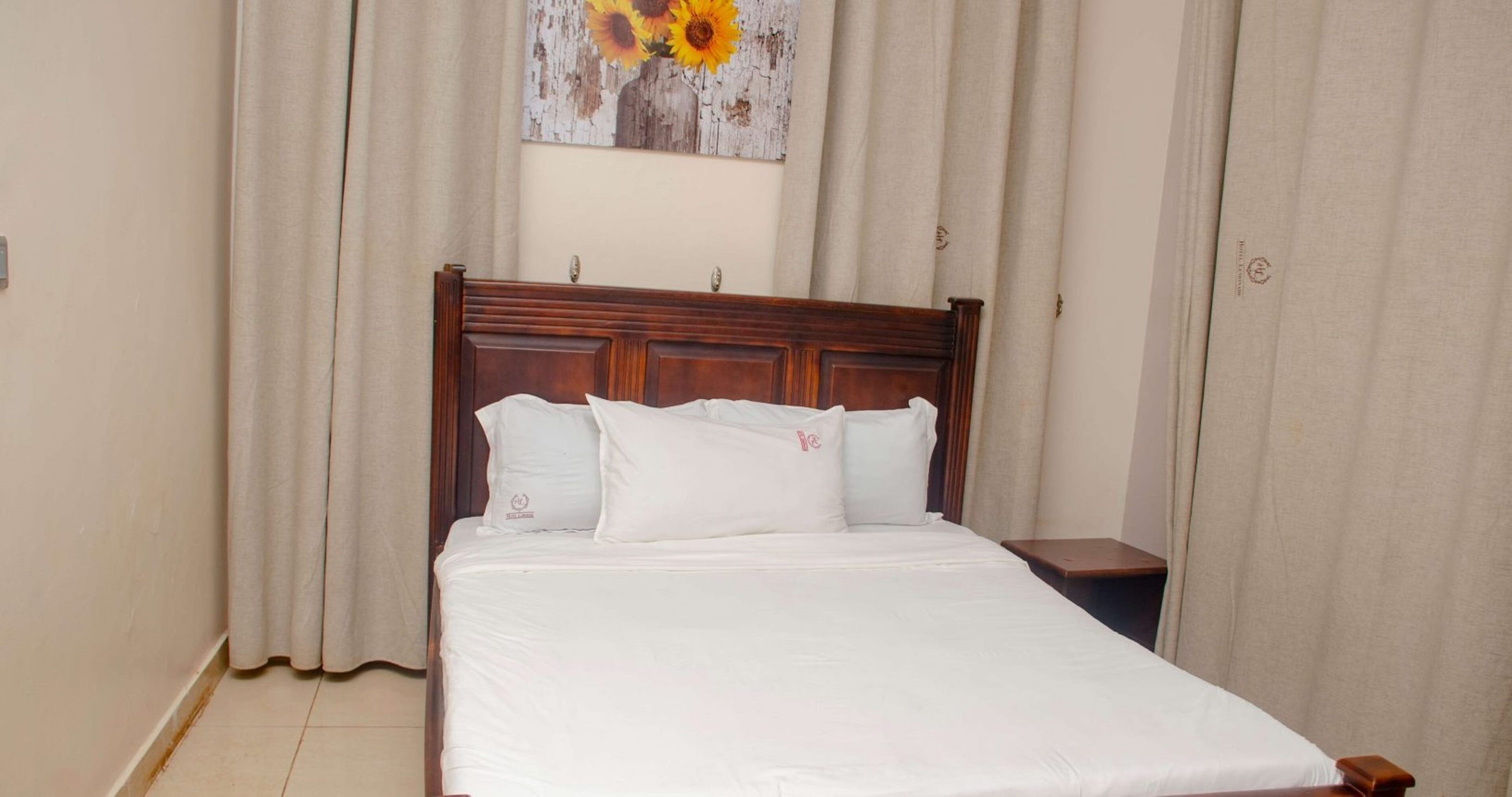 A neatly made bed with white linens and a wooden headboard in a hotel room.
