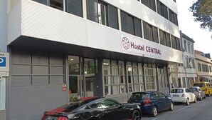 A building with a sign reading "Hostel CENTRAL" and a black sports car parked in front. - H. Central Funchal II (Funchal)