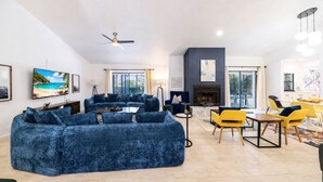 Una sala de estar moderna con un sofá azul grande, una chimenea y un comedor con sillas amarillas.