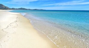 Ein Strand mit klarem türkisblauem Wasser und sandigem Ufer.