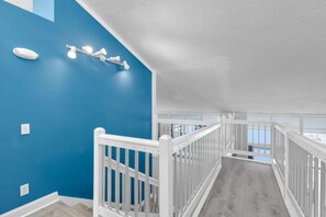 A staircase with white railings, a blue wall, and a ceiling light fixture.