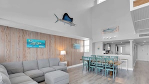 A spacious living area with a grey sectional sofa, teal chairs, and a wooden accent wall.