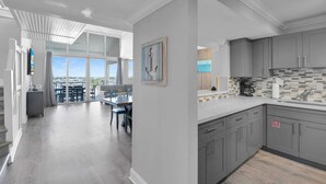 A modern kitchen with grey cabinets, a tiled backsplash, and a dining area with a view.