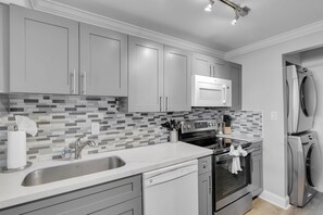 A modern kitchen with grey cabinets, a stainless steel sink, a microwave, and a built-in oven.