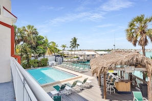 A pool area with lounge chairs, a bar, and a view of the ocean. - Waterfront Condo + Pool Downtown + Boat Slip (Key West)