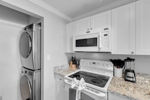 A kitchen with white cabinets, a stainless steel refrigerator, a microwave, a stove, and a blender. - Waterfront Condo + Pool Downtown + Boat Slip (Key West)