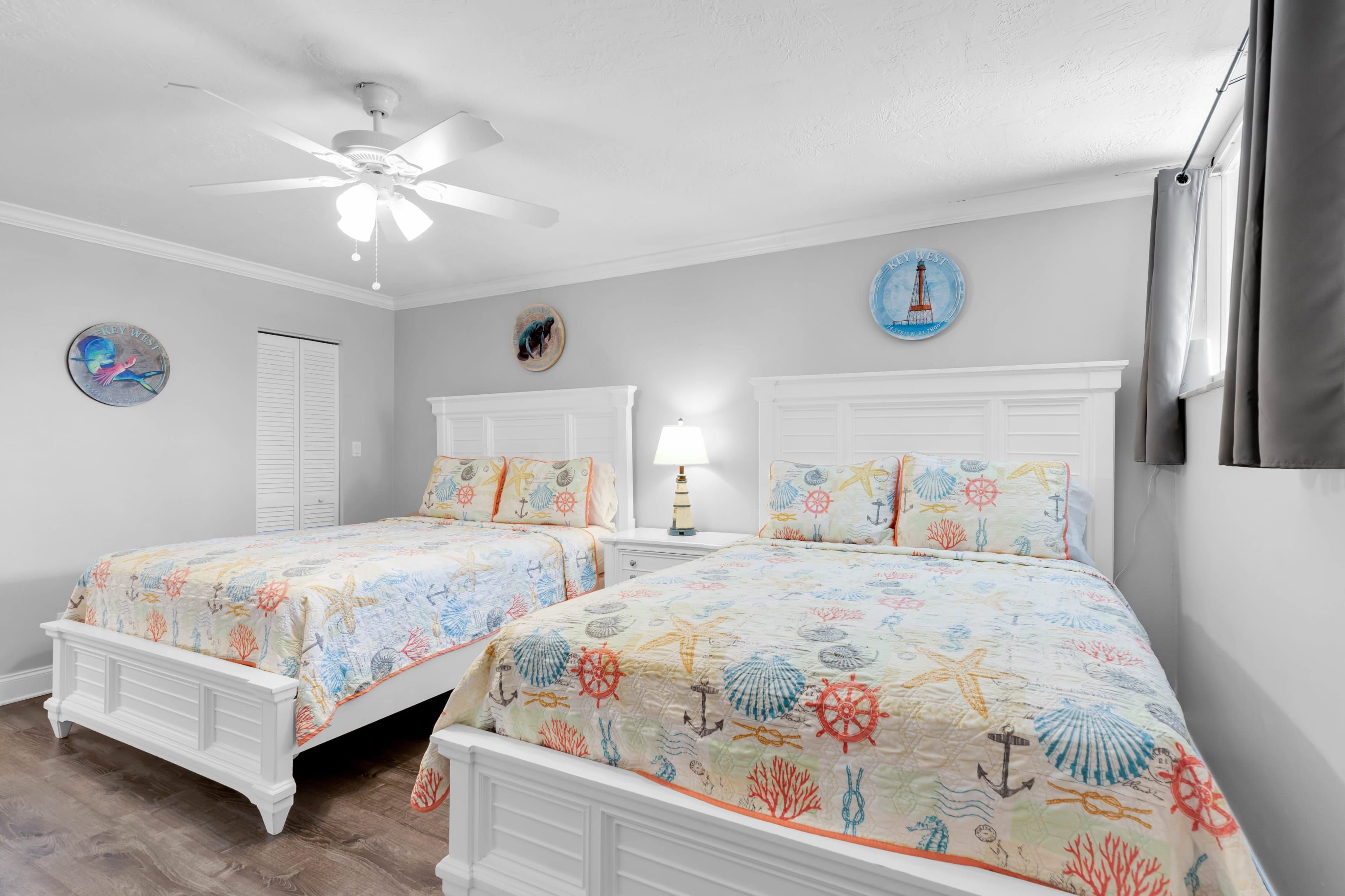 Une chambre avec deux lits, un ventilateur de plafond et une décoration sur le thème de la marine.