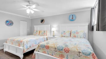 Une chambre avec deux lits, un ventilateur de plafond et une décoration sur le thème de la marine.