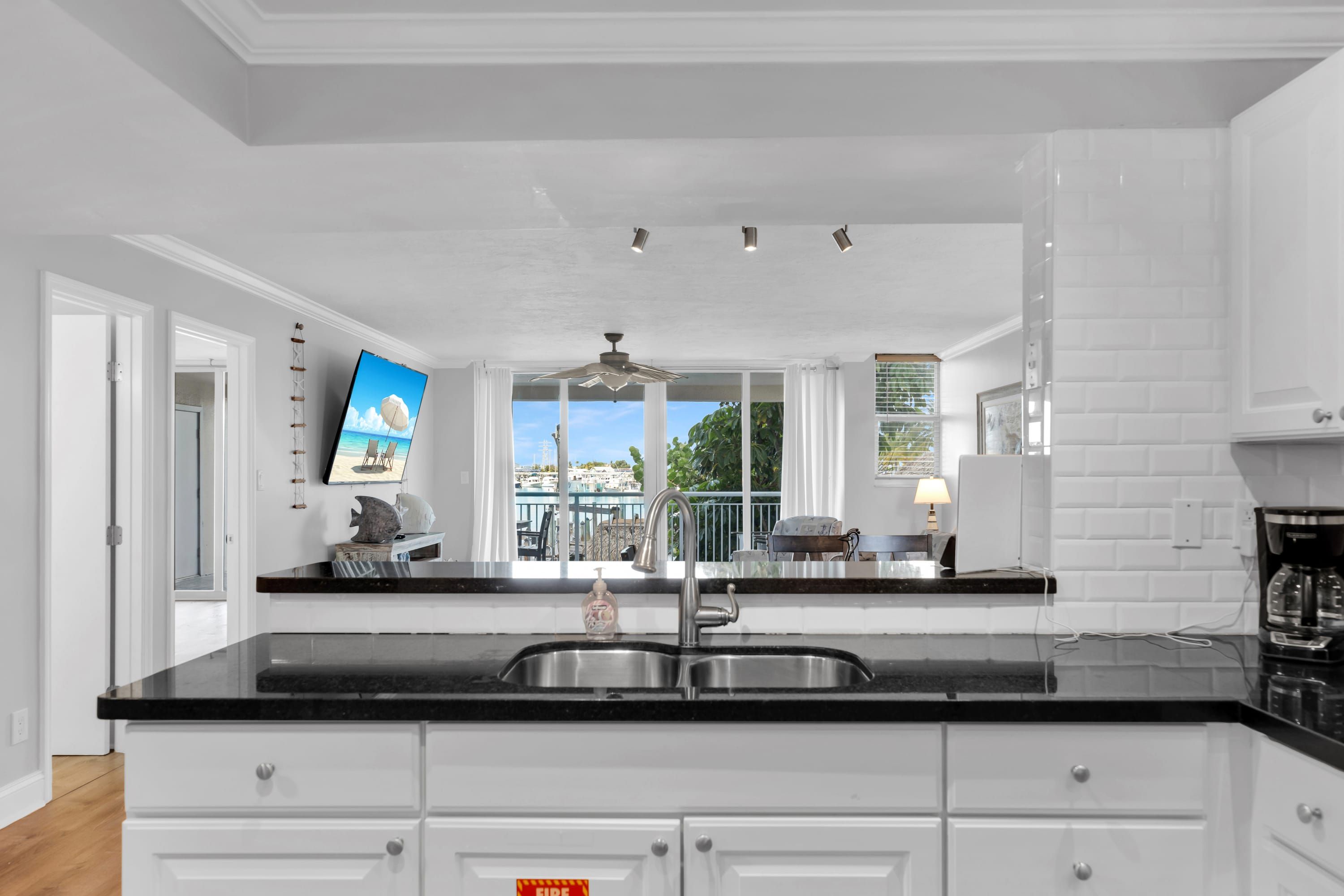 Una cocina moderna con encimera negra, pileta de acero inoxidable y muebles de cocina blancos.