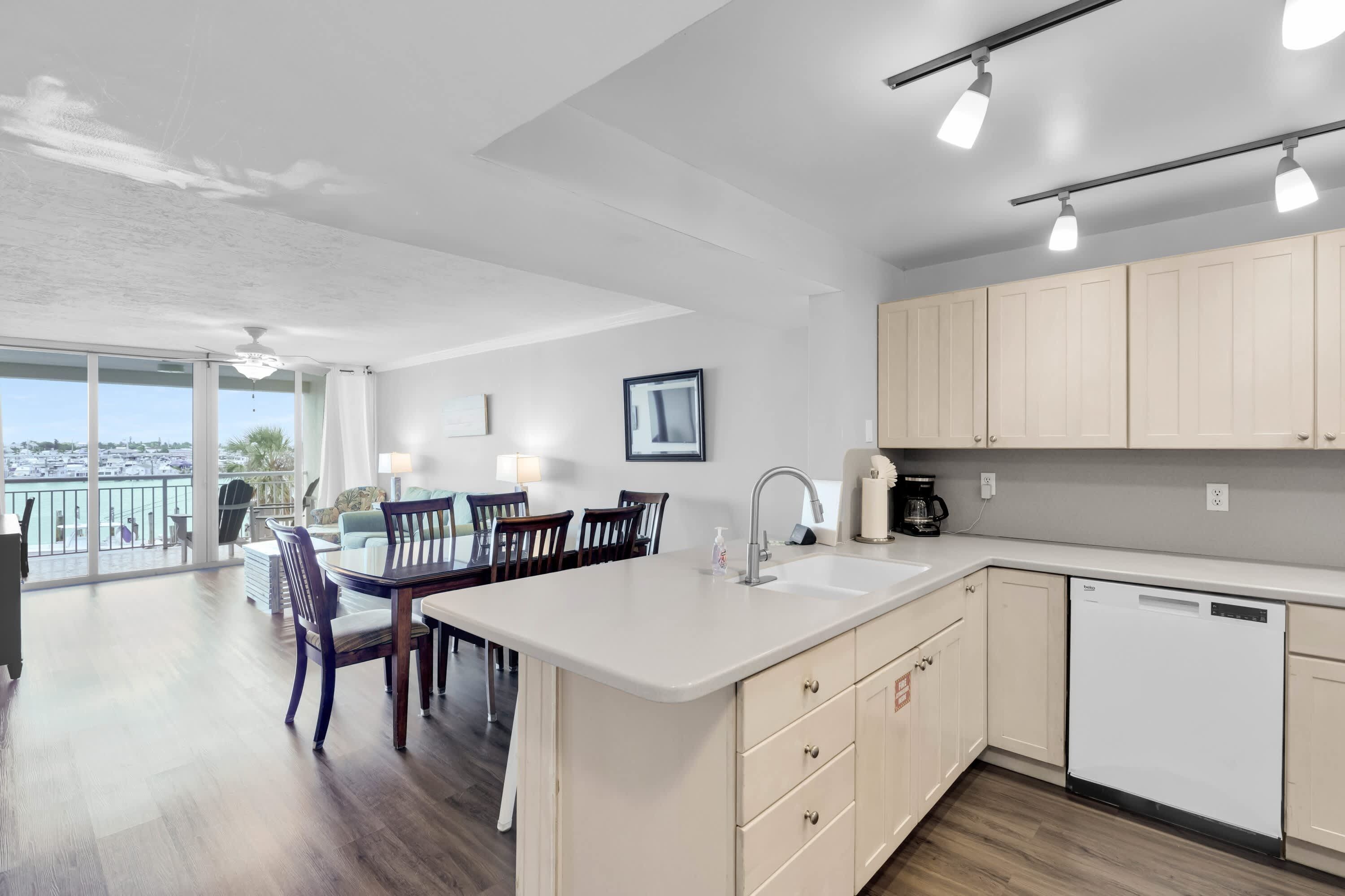 A modern kitchen with a large island, wooden chairs, and a dining table.
