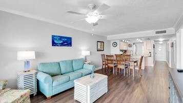 A living room with a blue sofa, a coffee table, and a ceiling fan.