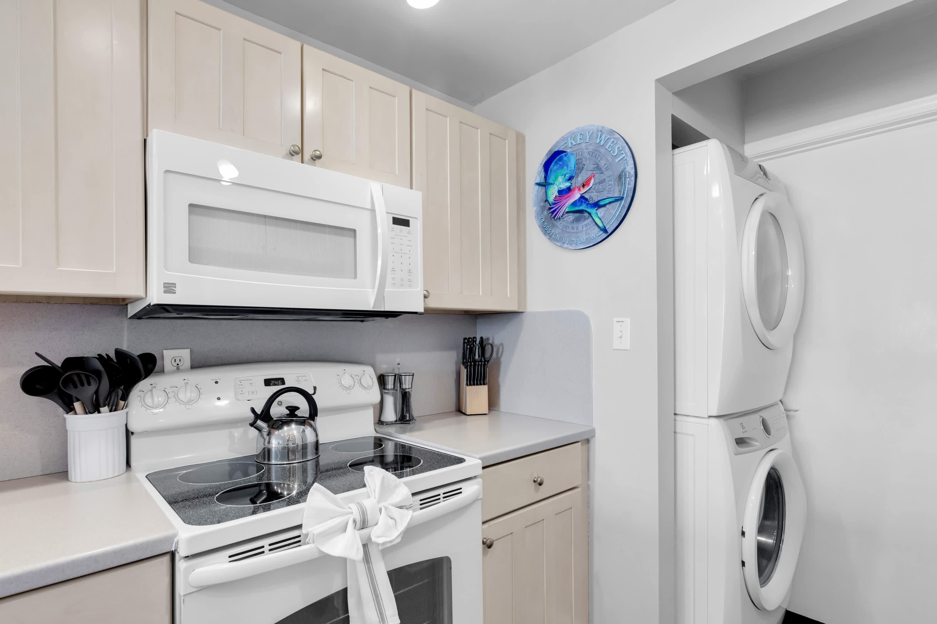 Une cuisine moderne avec des appareils électroménagers blancs, notamment un four à micro-ondes, une cuisinière et un lave-linge.