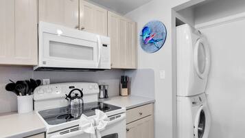 Une cuisine moderne avec des appareils électroménagers blancs, notamment un four à micro-ondes, une cuisinière et un lave-linge.