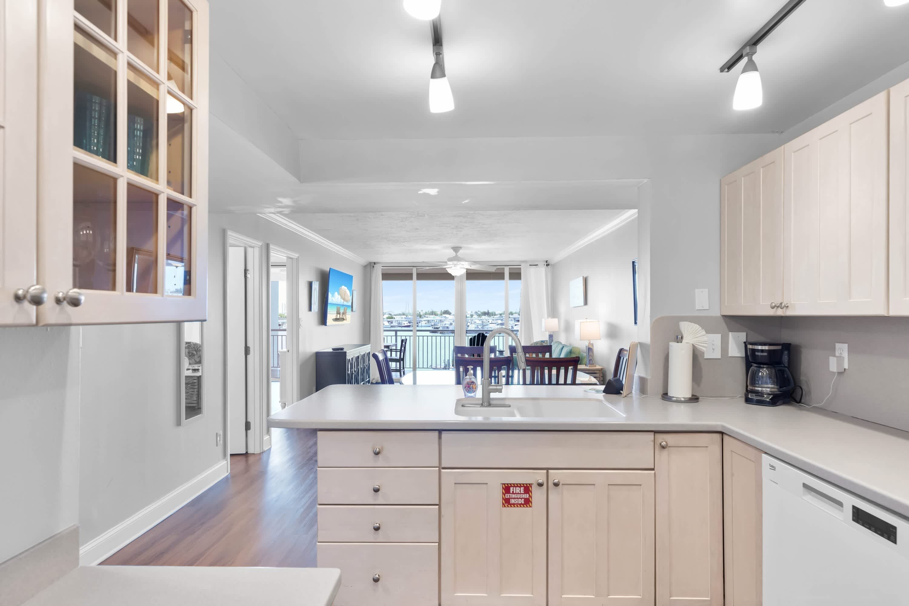 A modern kitchen with a central island, a dining area with a view, and a visible fire extinguisher sign.