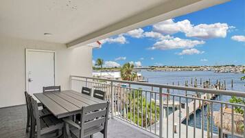 A balcony with a table and chairs, overlooking a marina with boats and a clear sky.