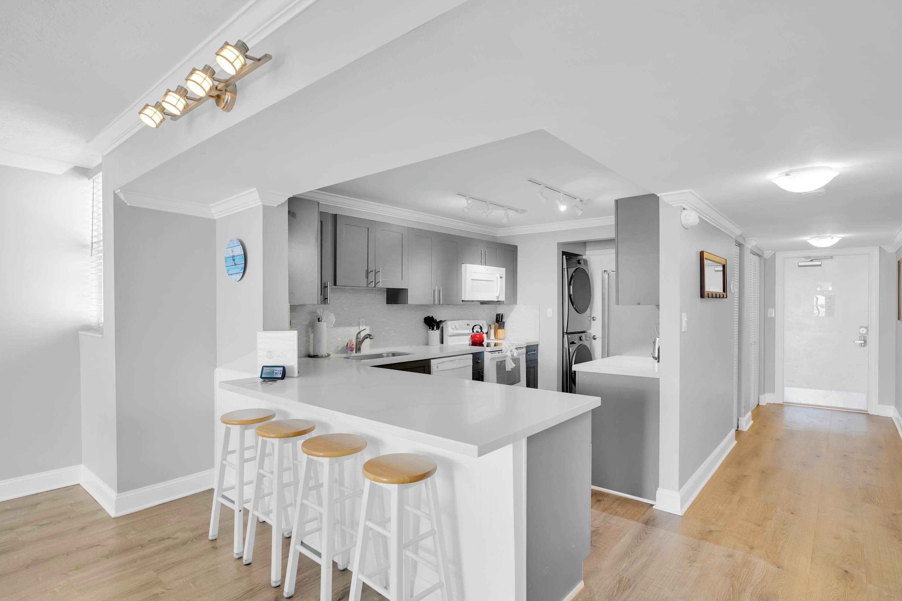 A modern kitchen with a central island, bar stools, and a built-in oven.