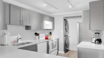 A modern kitchen with grey cabinets, a white countertop, stainless steel appliances, and a built-in microwave.