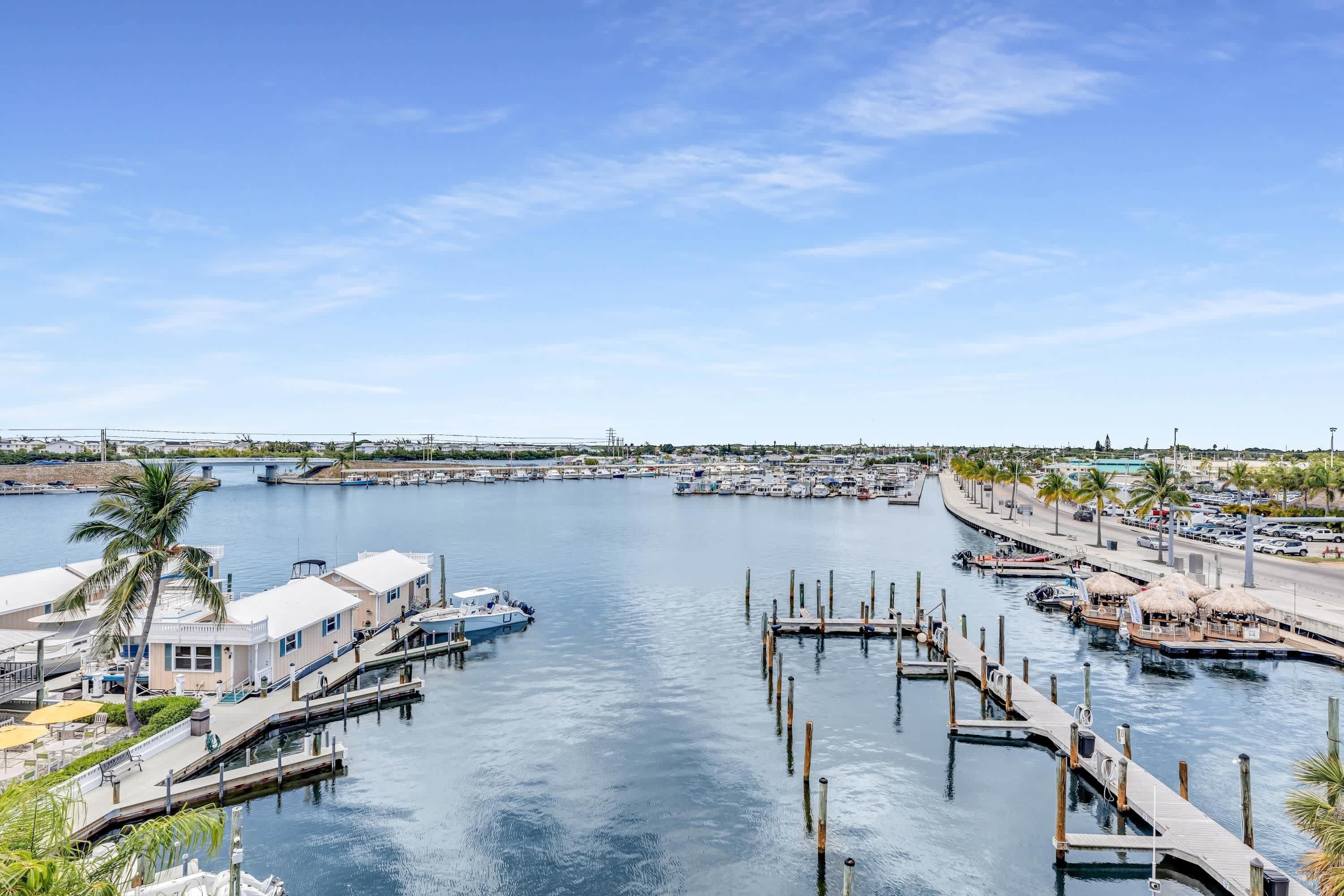 A marina with boats docked, a waterfront promenade, and buildings with visible balconies.