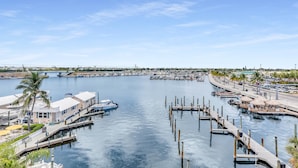 A marina with boats docked, a waterfront promenade, and buildings with visible balconies.