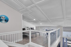 A spacious loft-style room with a high ceiling, a balcony with a railing, and a view of the water. - Penthouse Waterfront Dock Pool Condo Near Duval St (Key West)