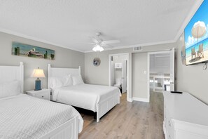 A bedroom with two beds, a ceiling fan, and a painting on the wall.