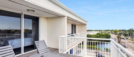 A balcony with a view of a body of water and a cityscape.