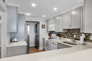 A modern kitchen with stainless steel appliances, a tiled backsplash, and white cabinetry.