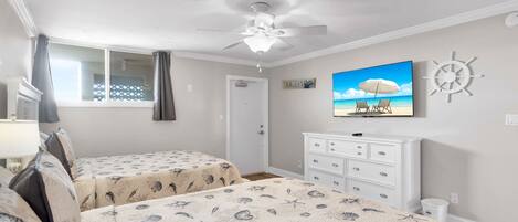 A bedroom with two beds, a ceiling fan, a TV, a dresser, and a wall clock.