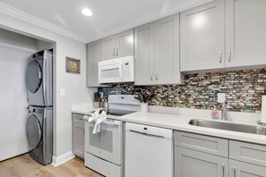Una cocina moderna con electrodomésticos de acero inoxidable, armarios blancos y un salpicadero decorativo.