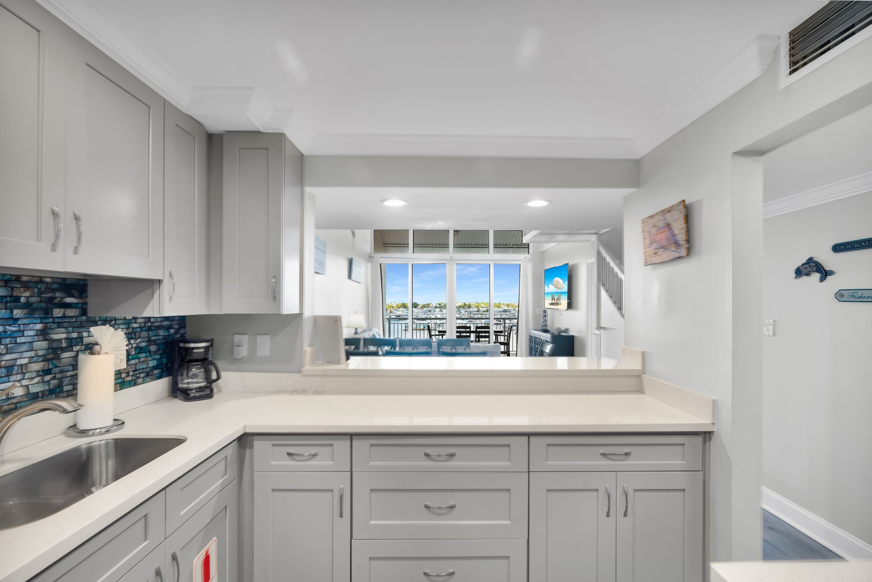 A kitchen with white cabinets, a coffee maker, and a view of the marina.