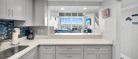 A kitchen with white cabinets, a coffee maker, and a view of the marina.