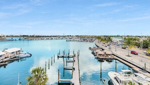 A marina with docked boats, a road with vehicles, and a clear blue sky.