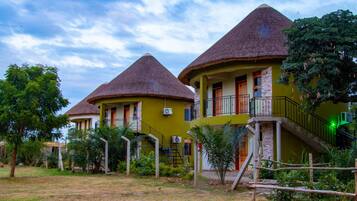 Un hôtel de style bungalow, avec des toits de chaume et une façade verdoyante.
