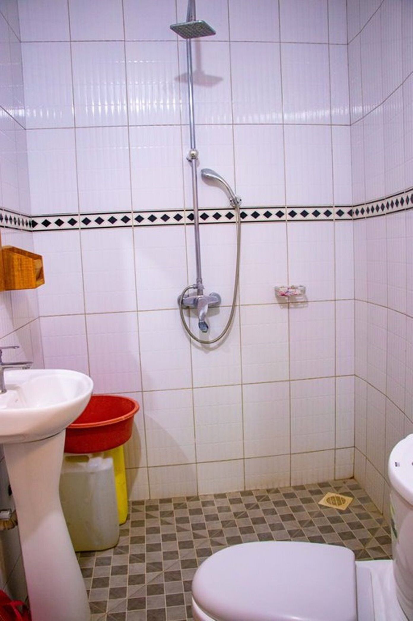 A small bathroom with a shower, a sink, and a toilet.