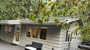 A modern house with a patio area featuring outdoor furniture and a fire pit. - Charming Geneva Bungalow (Bellingham)
