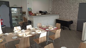 A dining area with a long table set for a meal, chairs, a counter with a coffee machine, and a wall with a brick pattern. - H. Central Funchal III (Funchal)