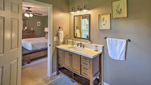 Une salle de bain équipée d’un meuble-lavabo à deux vasques, d’un miroir, d’un porte-serviettes et d’un ventilateur de plafond.