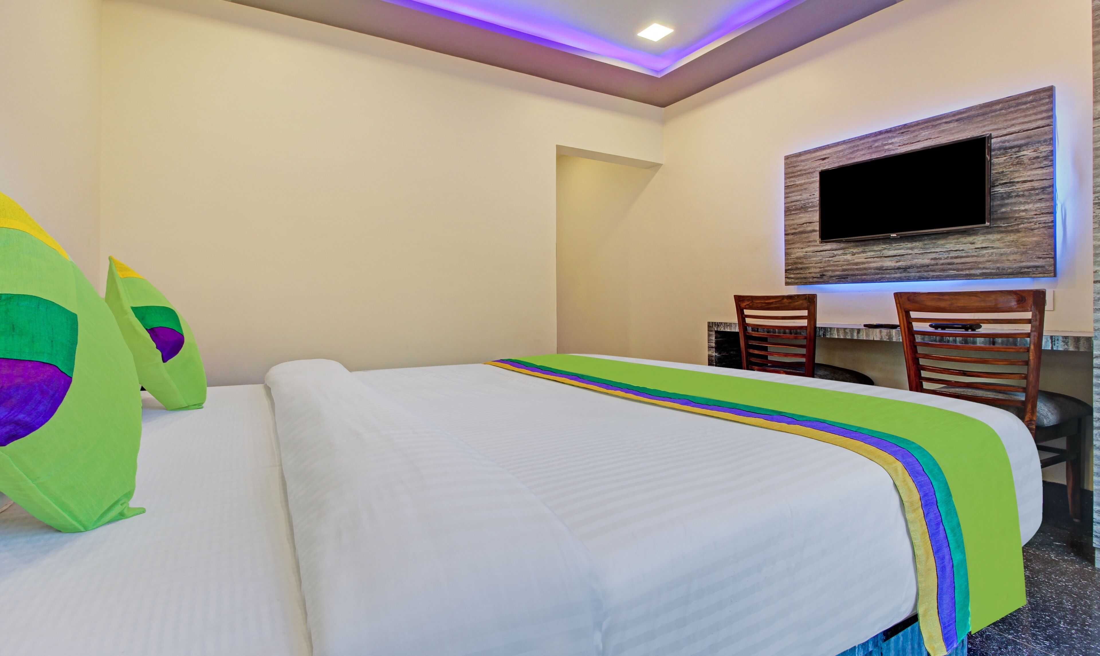 Een hotelkamer met een bed, een bureau en een televisie.